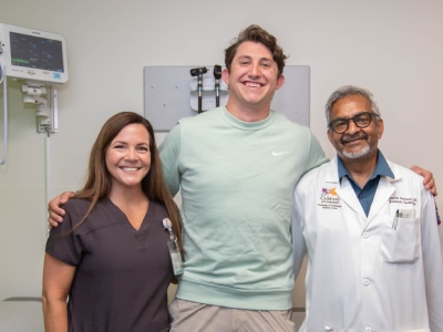 Tyler Free, Dr. Charles Gaymes, and Laura Kelly pose for picture in an exam room.